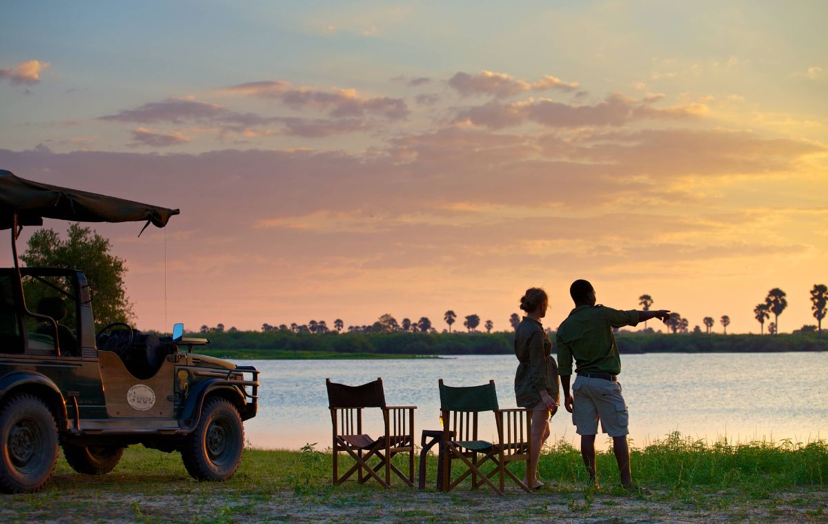 Tourist with guide on bank of Rufiji River for Nyerere National Park safari